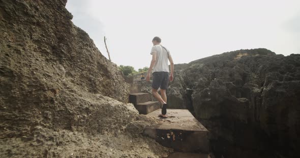 Following a Man Walking Up the Stone Stairs on the Rocky Cliff By the Ocean Male Tourist Ascending