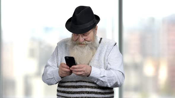 Retired Man with Beard Using Mobile Phone.