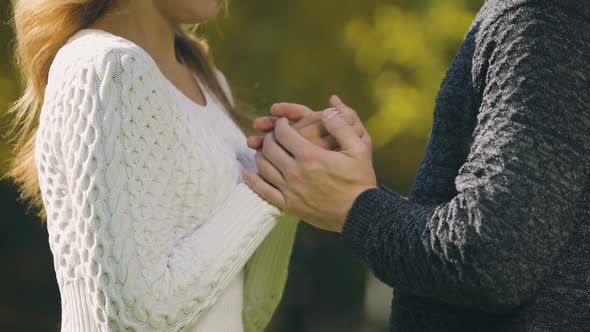 Frozen Couple in Sweaters Warming Hands in Autumn Park