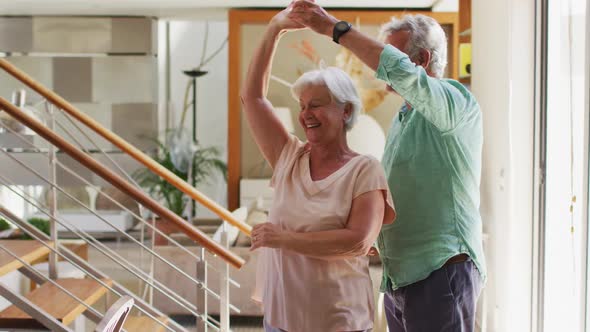 Happy senior caucasian couple dancing together at home