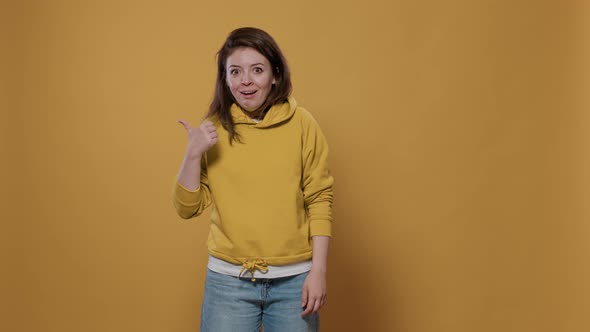 Funny Smiling Expressive Woman Doing Mocking Gesture with Thumbs Up Pointing to the Left and Right