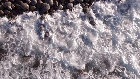 Winter Aerial Flight Top Over Waves Rolling on Artic Ocean Shore with Round Stones Ocean Waves at