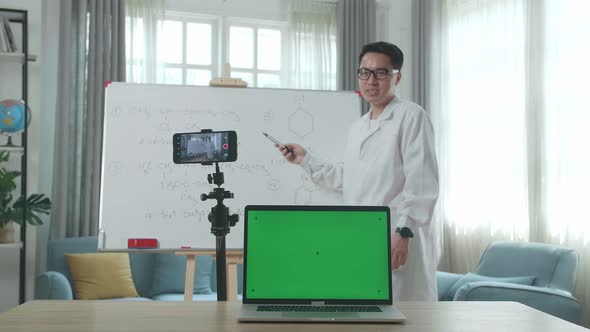 Male Teacher With Green Screen Laptop Shoots Video By Smartphone While Teaching Chemist At Home