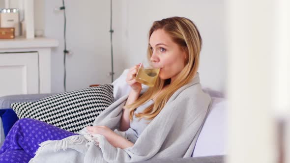 Woman having green tea in living room 4k