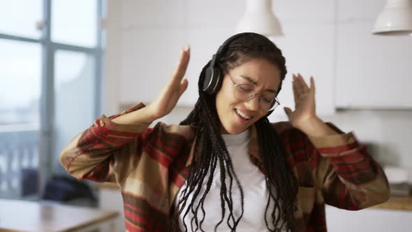 Portrait of the Young African American Woman Wearing Headphones Listening to the Music at Home