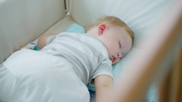 Caucasian baby boy toddler sleep on cozy pillow in kids bed with comfort in bedroom at home.