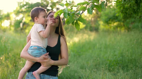 Happy Mother with Her Little Son in Arms in Park