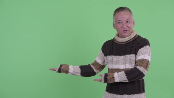 Happy Mature Japanese Man Talking While Showing Something