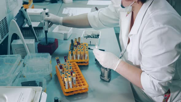 A Lab Worker Holds a Pipette Dispenser and Transfers Blood Samples From Covid 19 Coronavirus