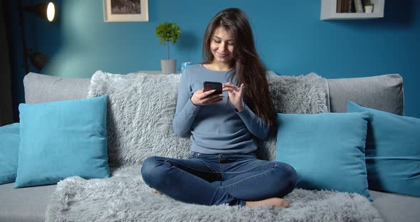 Brunette Lady Using Phone While Sitting on Sofa