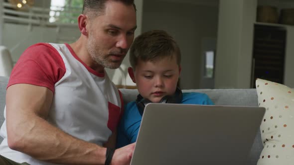 Caucasian father with son sitting in living room and using laptop