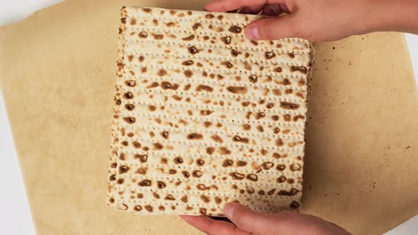 two female hands place a baked square matzah 