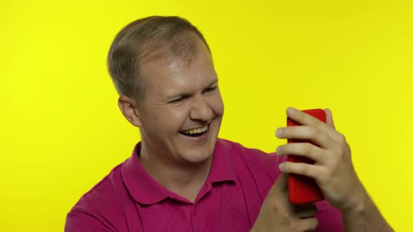 Young Man Posing in Pink T-shirt. Handsome Guy Using Mobile Phone, Watching Funny Videos Online