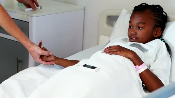 Female doctor measuring sugar level of sick girl with glucometer