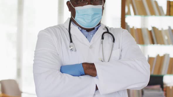 African american senior male doctor wearing white crossing his arms looking at the camera