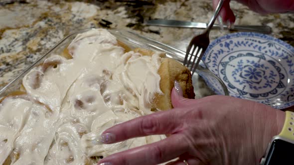 Plating a freshly baked and iced cinnamon roll to eat