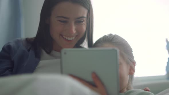 Smiling Mother Typing Pad Hugging Daughter Closeup