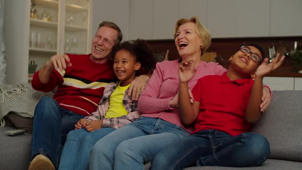 Carefree Grandparents and Joyful Multiethnic Children Watching Comedy Show on Tv