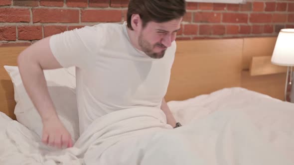 Casual Young Man Having Back Pain in Bed