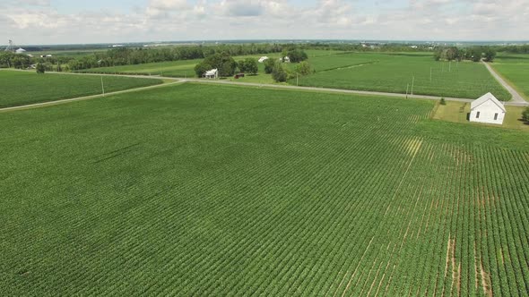 A small church sits in the middle of a Corn Field. Aerial drone shot surrounding this small church.