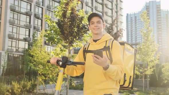 Young Smiling Courier on the Street of the Metropolis in the Rays of the Early Sun