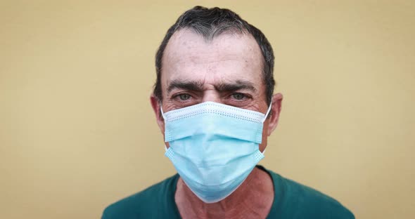 Senior man looking in camera while wearing surgical face mask for coronavirus outbreak