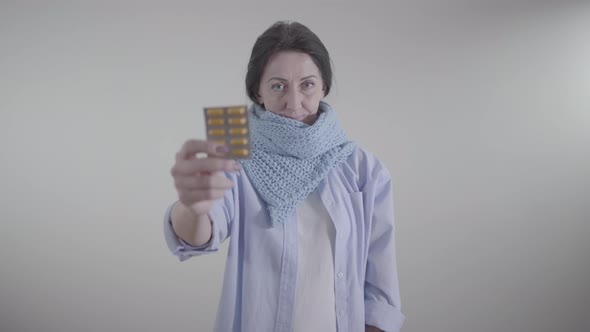 Portrait of Adult Caucasian Woman Holding Blurred Blister Pack of Pills. Brunette Lady Showing