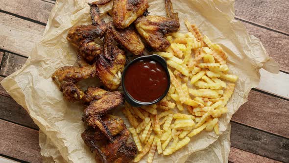 Appetizing Roasted Chicken Wings and French Fries with Barbecue Dip, Served on Baking Paper