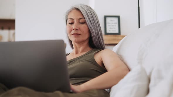 Concentrated Asian woman typing at laptop