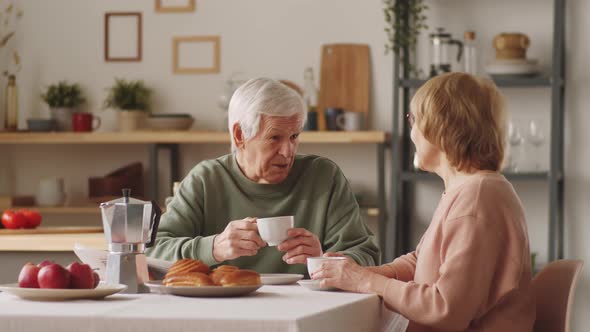 Happy Elderly Couple Chatting over Coffee at Home