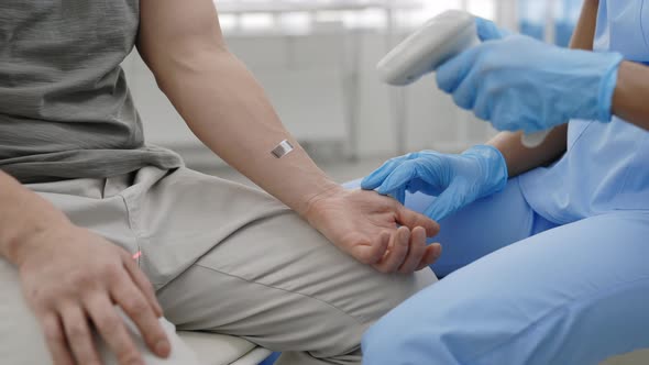 Crop View of Medical Worker on Protective Medical Gloves Scanning Bar Code on Patient Arm Before