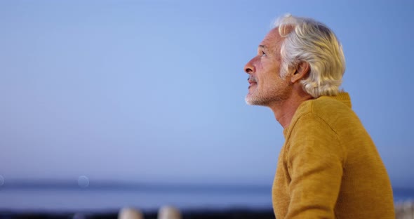 Senior man sitting outdoors against sky 4k