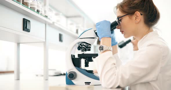 Young Scientist Looking Through Microscope in Laboratory