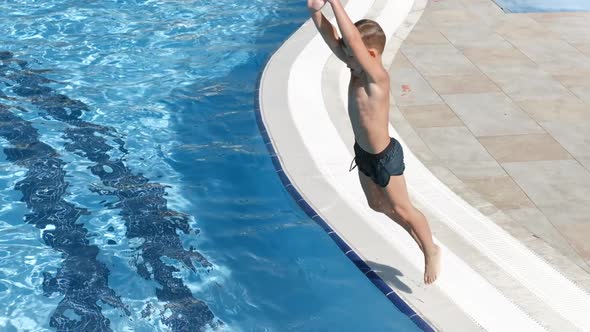 Active Tanned Boy Jumping in Swimming Pool Surrounded By Splashing Water Slow Motion