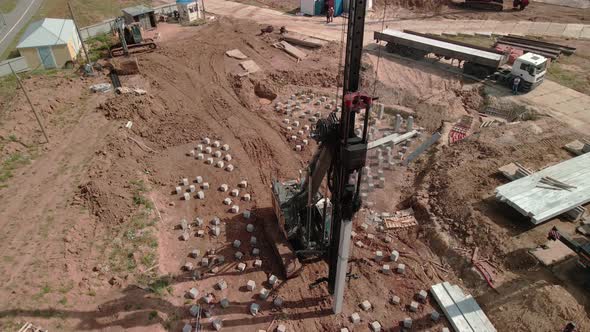 A Large Vertical Piledriving Crane Hammers Reinforced Concrete Piles Into the Ground at a