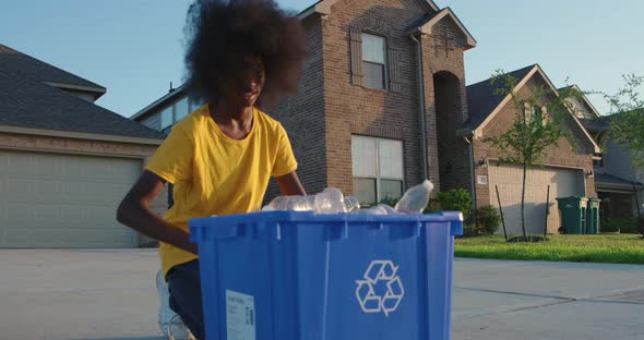 African American adolescence placing plastic bottles in recycle bin