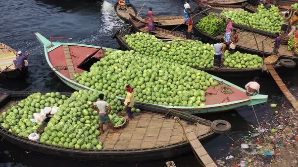 Aerial view of workers exchanging watermelons on boats along the Buriganga River.