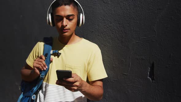 Mixed race man wearing headphones and using smartphone in the street