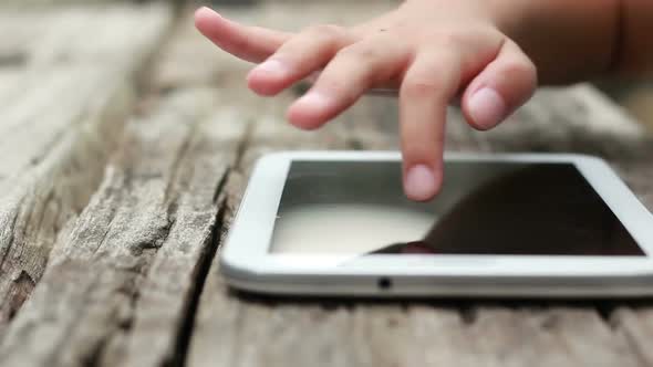 Close Up Child Hand Playing Tablet On Wood Table