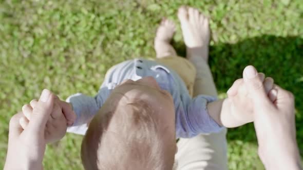 POV of Woman Helping Toddler Walking on Grass alt