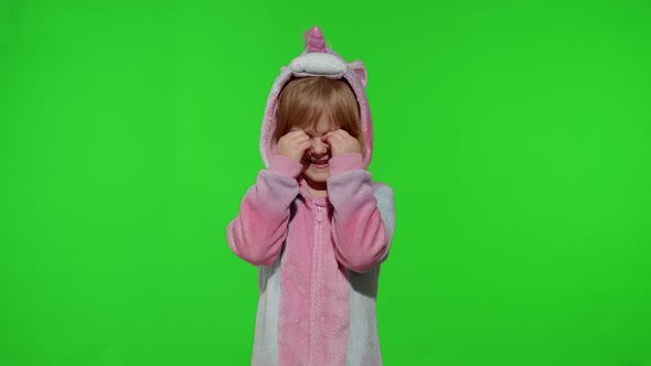 Little Blonde Child in Unicorn Costume Crying Wiping Tears with Her Hands on Chroma Key Background