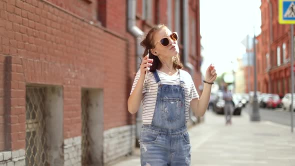 Pretty girl listening to music and dancing on the street