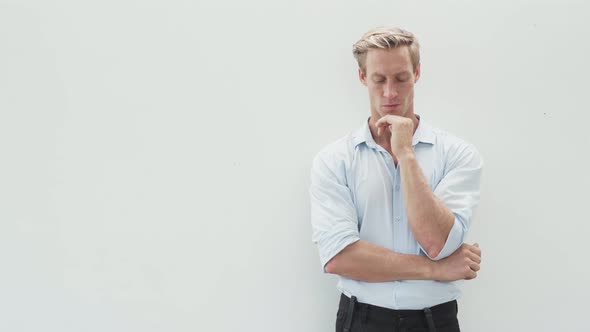 Portrait of Thoughtful Blond Man in Shirt with Crossed Hands on White Background