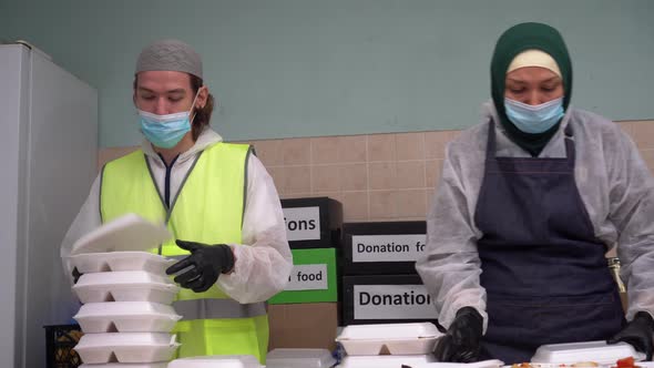 Muslim volunteers wearing a mask and gloves prepare free Iftar meals during Ramadan