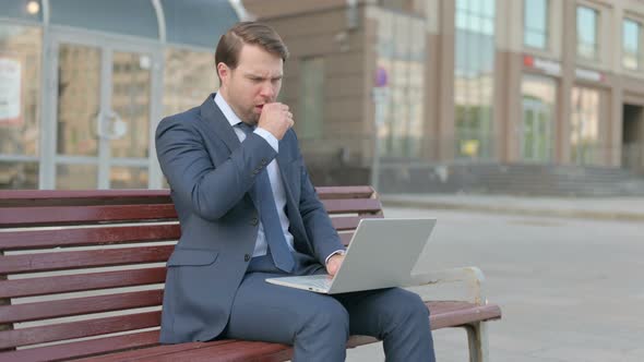 Coughing Businessman Using Laptop while Sitting Outdoor on Bench