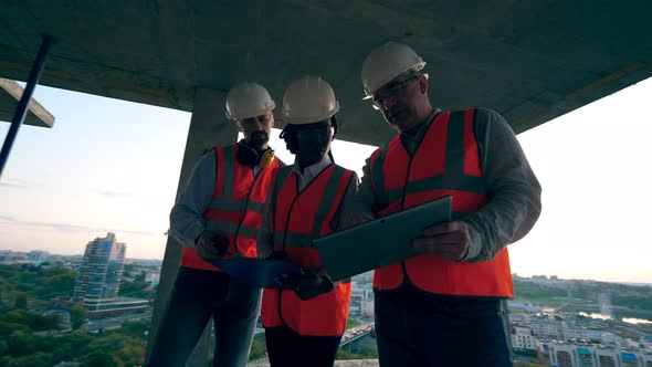 Engineers Are Talking at the Construction Site of a High-rise Building alt