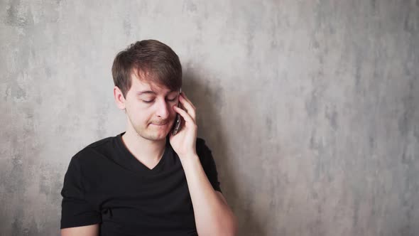 A Young Man with a Headache Speaks on the Telephone. Sick at Home Quarantine