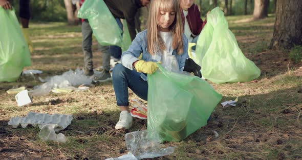 Kids Together with Adults which Holding Plastic Packs in Their Hands and Picking Up Rubbish