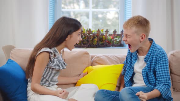 Portrait of Brother and Sister Quarrelling and Screaming at Each Other on Couch