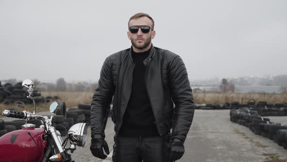 Brutal Biker in Sunglasses Crossing Hands and Looking in the Distance